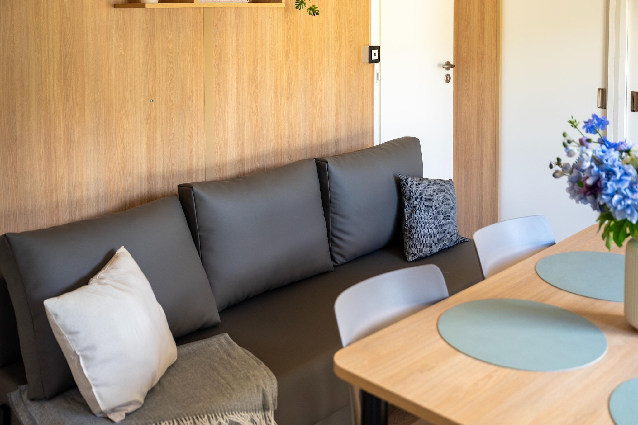 Une pièce moderne avec un canapé, une porte en bois et une table avec des chaises.