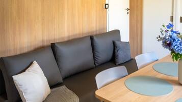 Une pièce moderne avec un canapé, une porte en bois et une table avec des chaises.