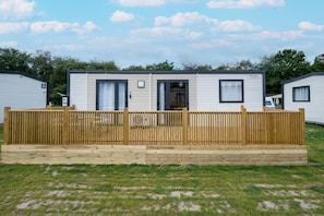 A mobile home with a fenced deck, a door, and a window.