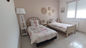 A bedroom with two beds, a nightstand, a lamp, decorative wall mirrors, and a window with blinds. - Gîte in the heart of nature, peace and quiet guaranteed, animals welcome. (Diges)