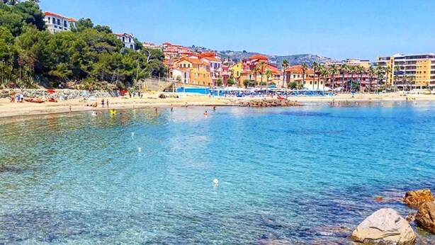 A coastal beach with clear water, rocks, and colorful buildings in the background. - Guest house Cà du Sciu Megu (Civezza)