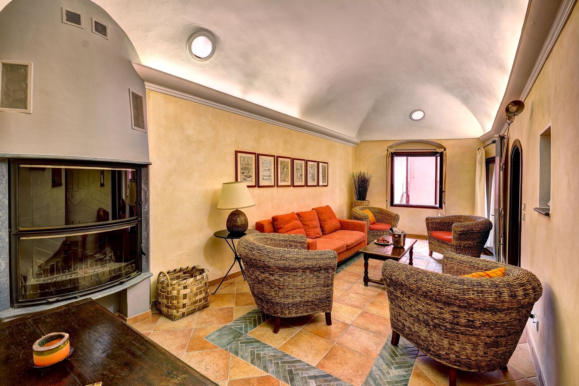 Una sala de estar con chimenea, un sofá, sillas de mimbre y una mesa de comedor.