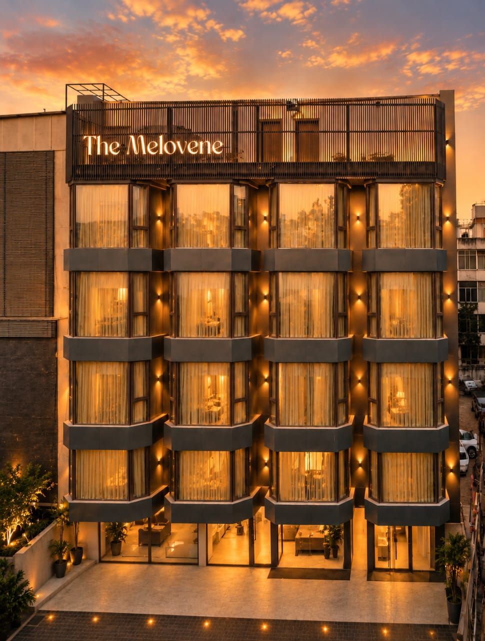 A multi-story hotel with a modern facade, balconies, and a sign reading 'The Melovene.'