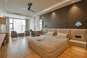 A modern hotel room with a large bed, a desk, a chair, and a ceiling fan. - Melange Hotel - Golf course road (Gurugram)