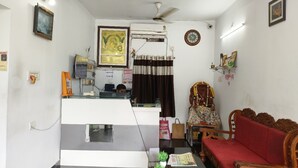 A living room with a sofa, a small table with a plant, a ceiling fan, and a wall-mounted air conditioner. - Binayak Palace OD (Kendrapara)