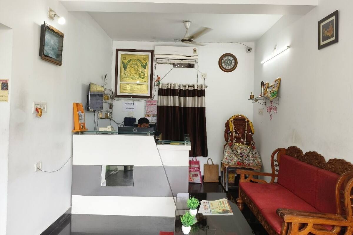 A living room with a sofa, a small table with a plant, a ceiling fan, and a wall-mounted air conditioner.