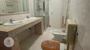 A bathroom with two sinks, a shower, and a toilet. - Apartment Ramina (San Giuseppe - Comacchio)