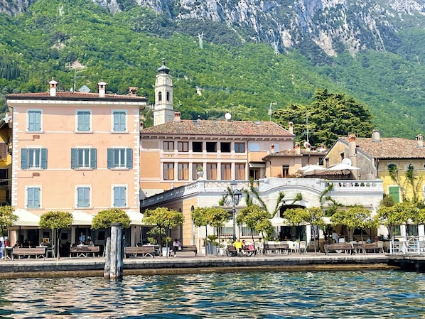 Ein Gebäude am Wasser mit Balkonen, einer Brücke und einem Berg im Hintergrund.
