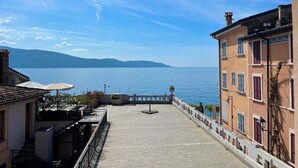 Eine Terrasse mit Meerblick, ein Gebäude mit Balkonen und ein klarer Himmel.