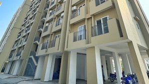 A high-rise residential building with multiple balconies, a covered parking area, and a streetlight.