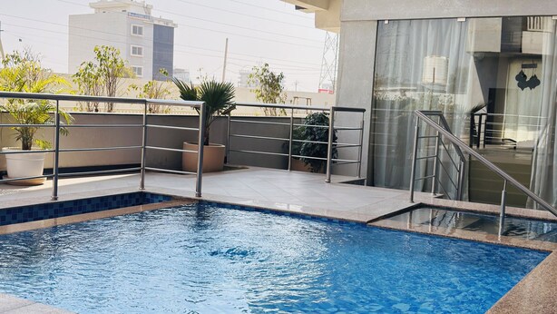 A swimming pool with a tiled edge, a metal railing, and a building in the background.
