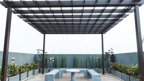 A covered outdoor patio with a pergola, seating area, and potted plants.