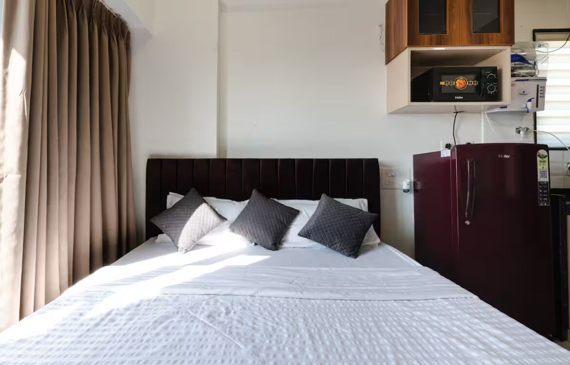 A bed with a headboard, a wardrobe, and a microwave above it.