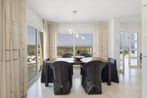 A dining area with a large table, chairs, and a view of the outdoors. - Villa with Pool and Spectacular Sea Views (Pals)