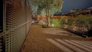 A courtyard with a tree, a brick wall, and a building in the background. - In Corte - Rooms in Florence (Florence)
