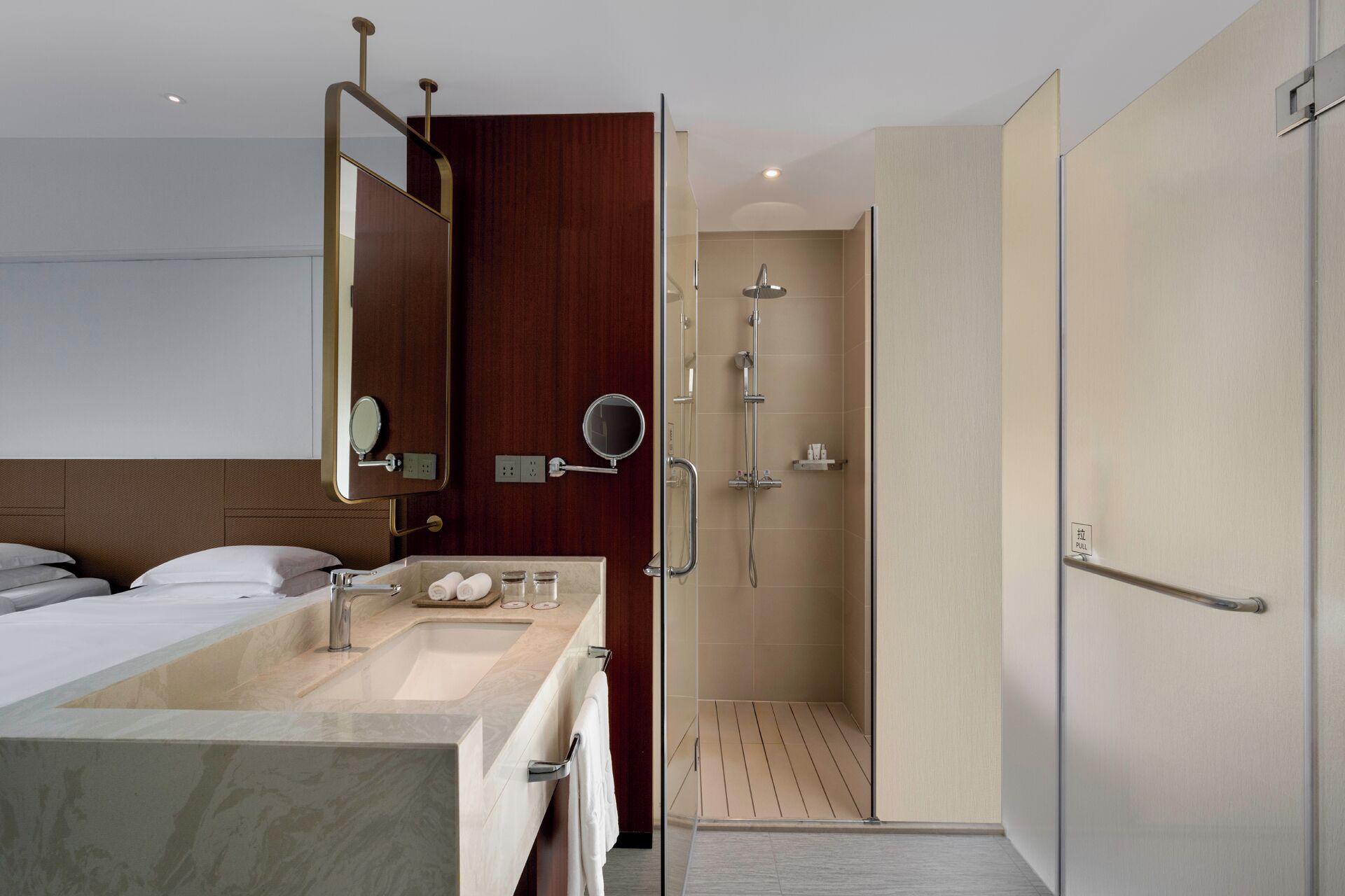 A modern hotel bathroom with a shower, a sink, and a mirror.