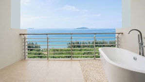 Un baño con bañera, vistas al mar y un balcón con barandilla.