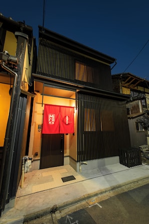 A building with a dark exterior, a red entrance sign, and a visible door.
