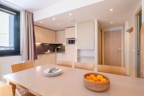 A modern kitchen with a dining area, a microwave, and a basket of oranges on the table. - Résidence Pierre Vacances with balcony (Flaine)