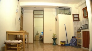 A hallway with a wooden table, a trash bin, a broom, and a potted plant. - LA CASA DE VIDA (Cusco)
