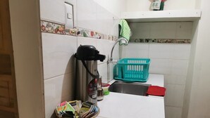 A small kitchen with a coffee maker, a basket of snacks, a sink, and a green basket. - LA CASA DE VIDA (Cusco)