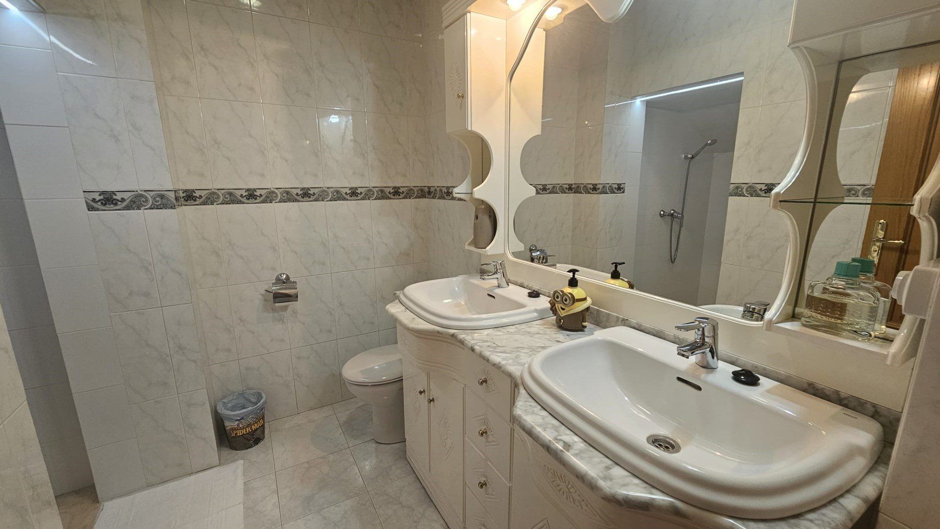 A bathroom with two sinks, a toilet, a shower, and a mirror.