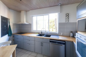 Une cuisine avec des meubles de couleur grise, un plan de travail en bois, un évier et une fenêtre.
