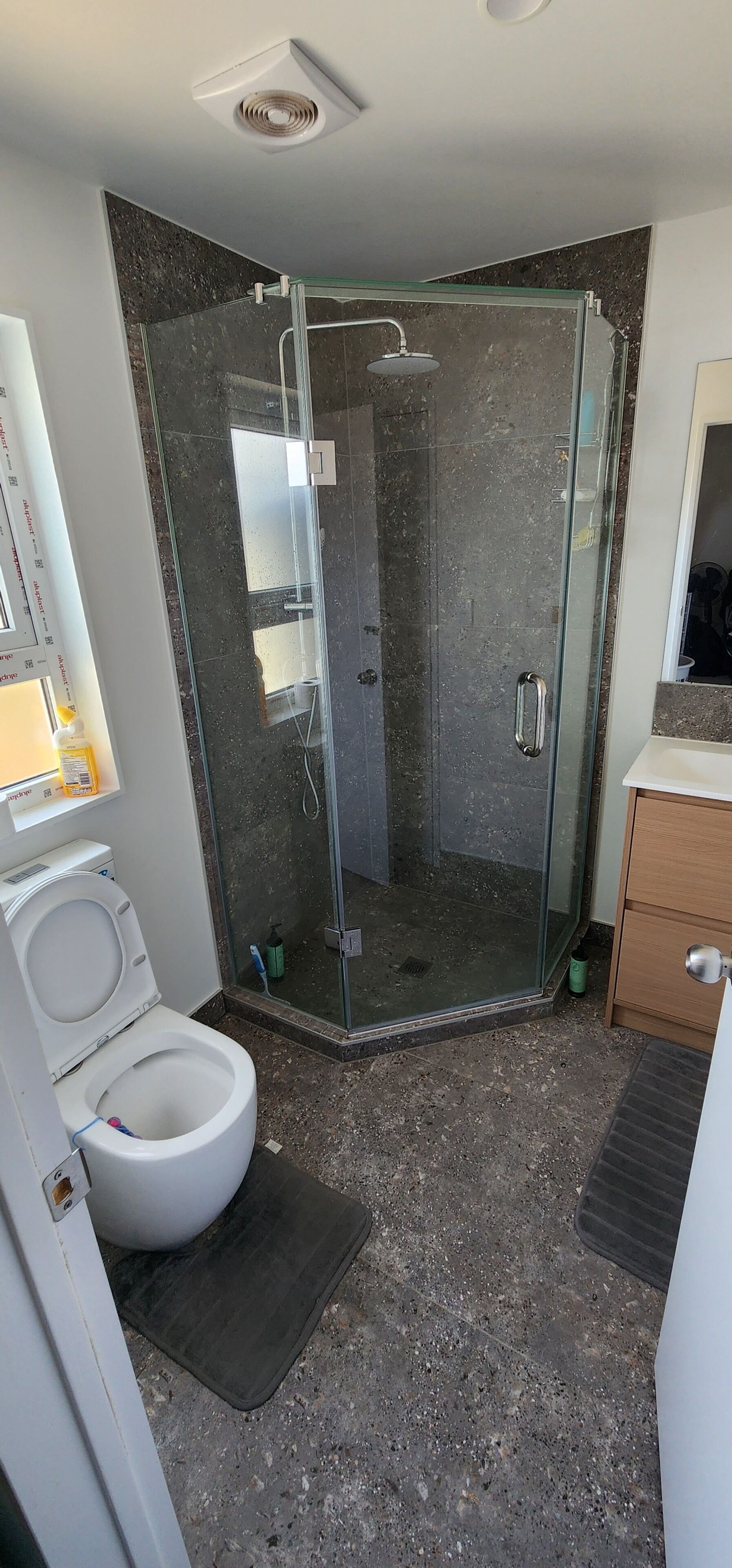 A bathroom with a glass shower enclosure, a toilet, and a sink.