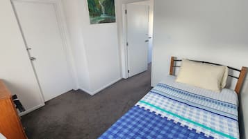 Ein Schlafzimmer mit einem Bett, einem hölzernen Kopfteil, einem Wandbild und einer Tür.