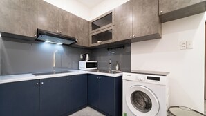 Una cocina moderna con armarios grises, microondas integrado y lavadora de carga frontal.