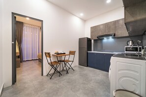 Eine kleine Küche mit Essbereich, einem Kühlschrank, einer Mikrowelle und einem Spülbecken.
