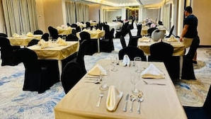 A banquet hall with tables set for dining, a waiter in service uniform, and a carpeted floor. - Wescott Plaza Hotel Apartments L.l.c (Dubai)