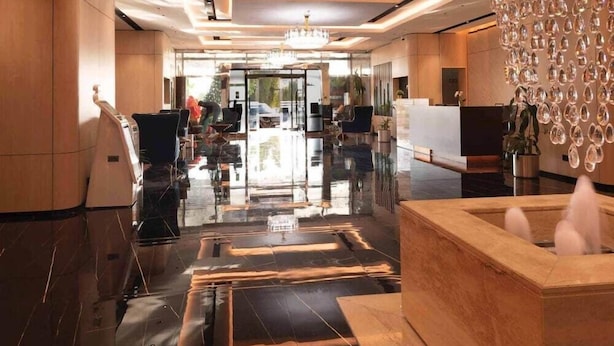 A modern lobby with a reception desk, seating area, and a decorative water feature. - Wescott Plaza Hotel Apartments L.l.c (Dubai)