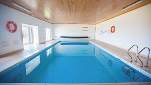 Een binnenzwembad met houten plafond, reddingsboeien en een helder zicht op het zwembad.