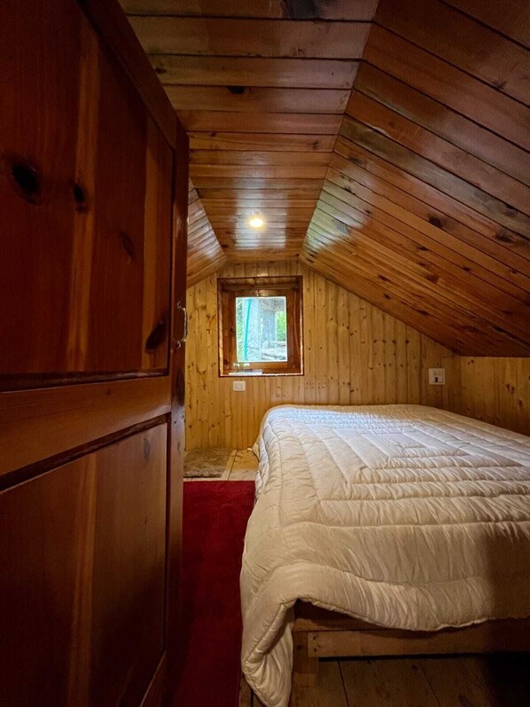 Una habitación de madera con una cama, una ventana y una puerta.
