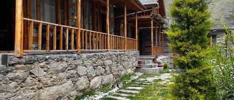 A wooden building with a stone wall and a stone pathway leading to it.
