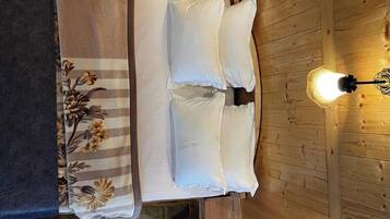 A wooden cabin-style room with a bed, two wall-mounted lights, and a wooden staircase.
