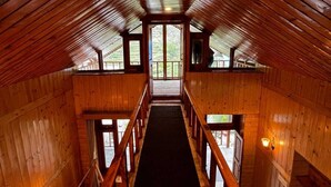 Een houten interieur met een centrale trap die leidt naar een open doorgang.