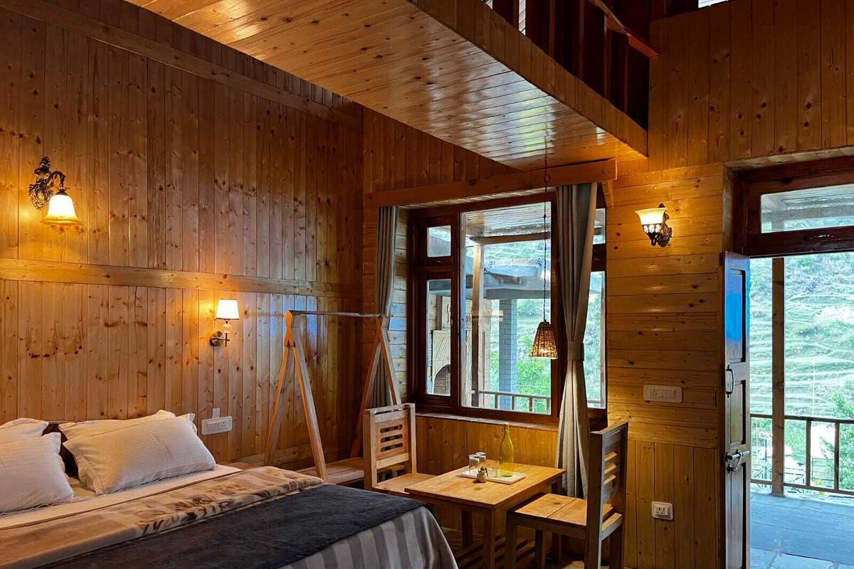 Una habitación de cabaña de madera con una cama, una mesa y una silla.