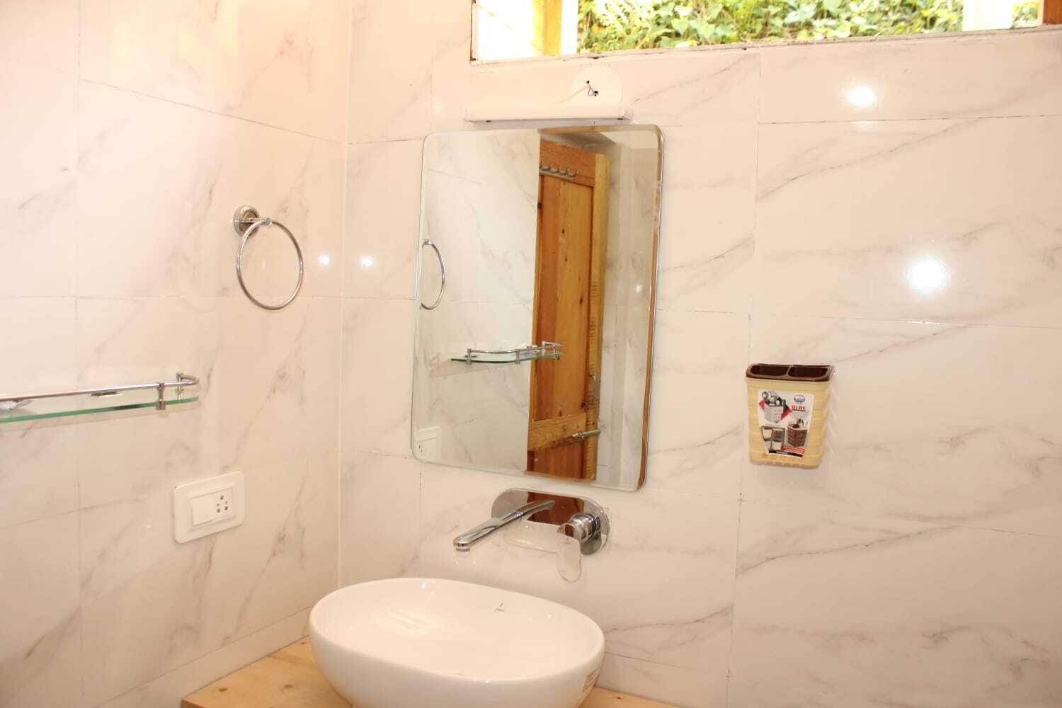 Une salle de bain avec un lavabo blanc, un miroir, un porte-serviettes et un espace douche.