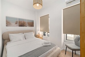A bedroom with a bed, bedside table, lamp, window with blinds, and a chair. - Kastella Retreat | Private Terrace + Yard | 2BR | Professionally Managed | Piraeus Seafront District (Piraeus)