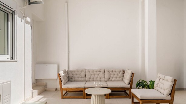 A minimalist living room with a sofa, two chairs, a small round table, and a radiator. - Kastella Retreat | Private Terrace + Yard | 2BR | Professionally Managed | Piraeus Seafront District (Piraeus)