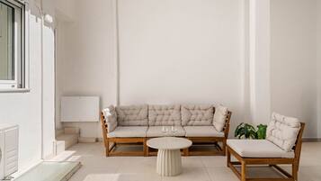 A minimalist living room with a sofa, two chairs, a small round table, and a radiator.