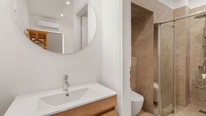 A modern bathroom with a white sink, mirror, and glass shower enclosure. - Kastella Retreat | Private Terrace + Yard | 2BR | Professionally Managed | Piraeus Seafront District (Piraeus)