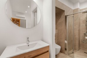 A modern bathroom with a white sink, mirror, and glass shower enclosure. - Kastella Retreat | Private Terrace + Yard | 2BR | Professionally Managed | Piraeus Seafront District (Piraeus)