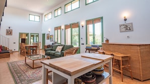 A spacious living area with high ceilings, multiple windows, a dining set, a sofa, and a bar area. - Anahuacal-li on the hilltop over the sea (Begur)