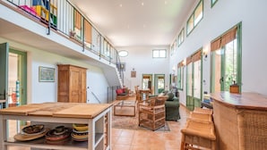 A spacious loft with a high ceiling, a dining area, a seating area, and a staircase leading to an upper level. - Anahuacal-li on the hilltop over the sea (Begur)
