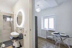 Ein modernes Badezimmer mit einem großen Spiegel, einem weißen Waschbecken und einer Duschkabine aus Glas.