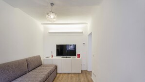 A modern living room with a sofa, TV, and a pendant light. - Cute Nest Near the Center by Wonderful Italy (Genoa)