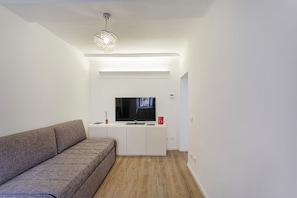 Ein modernes Wohnzimmer mit einer Couch, einem Fernseher und einer Pendelleuchte.